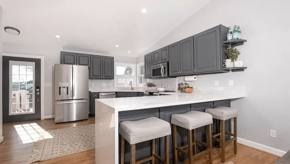 A stylish kitchen with an island, stools for counter seating, and gleaming stainless steel appliances, all set in an inviting, contemporary environment. The island is perfect for casual dining or sharing morning coffee, and the layout encourages interaction across the kitchen and living areas.